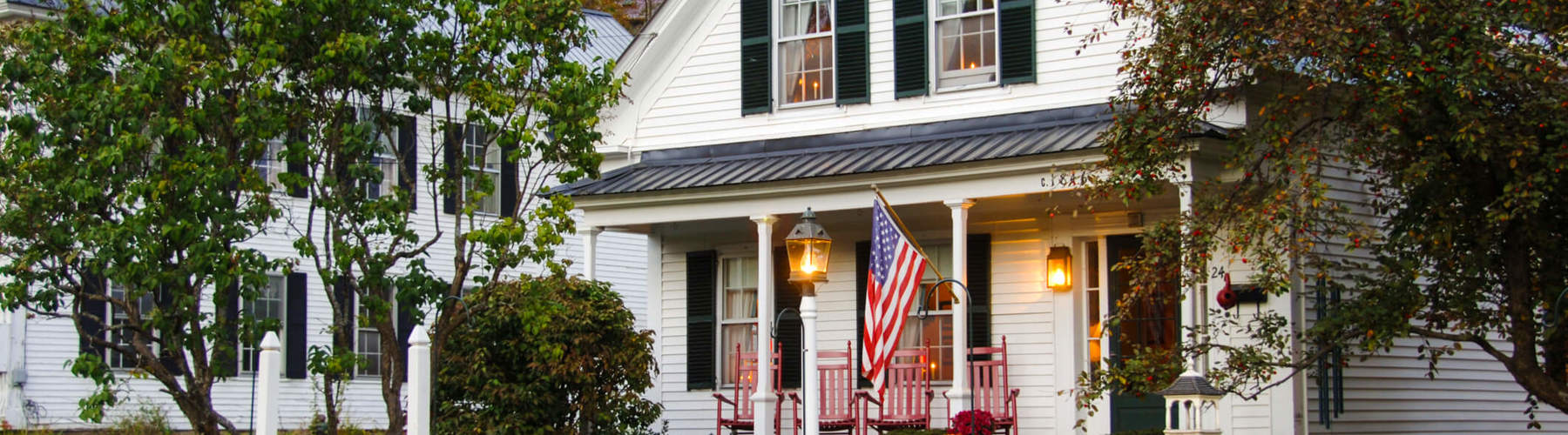 A charming house with a white picket fence adorned by an American flag